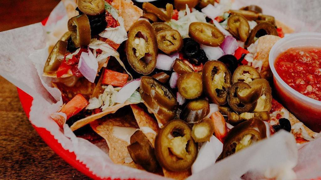 Nachos · Homemade tortilla chips topped with shredded cheese, queso, lettuce, tomato, onion, black olives, and fresh jalapeños.