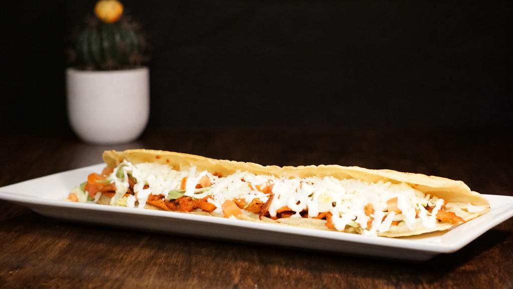 Machete · A large, footlong fried tortilla stuffed with your meat of choice, lettuce, tomato, queso fresco, and sour cream! It gets its name because of the shape of the tortilla!