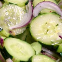 Cucumber Salad · Striped sliced cucumbers and julienne red onions in a white vinegar with oregano, basil, par...