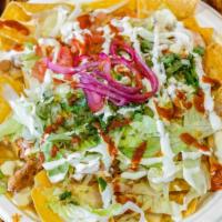 Nacho Fiesta Tray · Tray filled with Crispy tortilla chips, topped with refried beans, cheese sauce, lettuce, to...