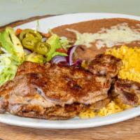 Carne Asada · Two thin slices of juicy steak served with rice, beans, lettuce, avocado slices, onions, and...