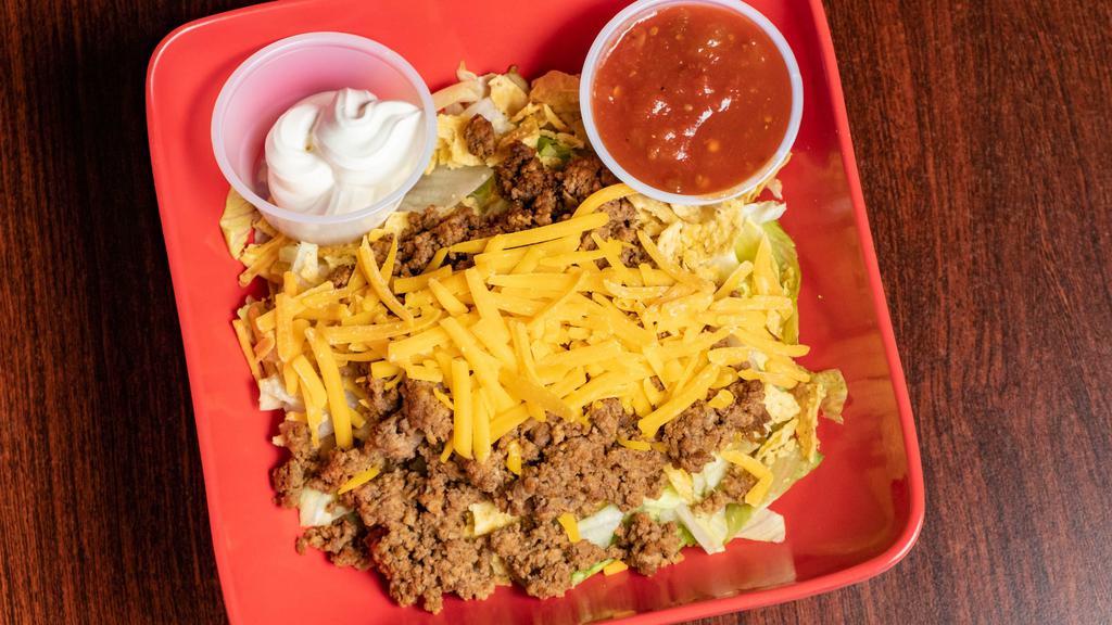 Taco Salad · A crisp bed of lettuce, covered in crumbled corn tortilla chips, our beef taco meat, tomato, onion, black olives and shredded cheese. Served with picante sauce and sour cream.