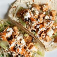 Buffalo Chicken Tacos · Diced buffalo chicken inside a warm flour tortilla with ranch on a bed of lettuce and blue c...