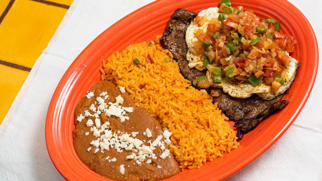Carne Ranchera · Grilled skirt steak, topped with two huevos ranchero’s and ranchero sauce. Served with Mexican rice and refried beans.