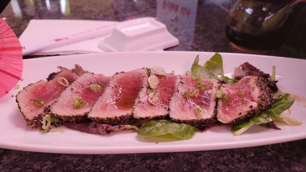 Pepper Tuna · Seared pepper tuna with ponzu sauce and spring mix salad on the bottom.