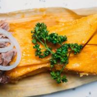 Tamal · Freshly grated corn meal slowly cooked with roasted pork, wrapped in a corn husk and topped ...