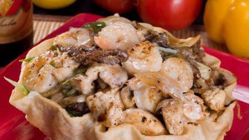 Taco Salad Deluxe · Fried flour tortilla bowl filled with lettuce, rice, grilled chicken, steak, shrimp, onions and bell peppers topped with cheese sauce.