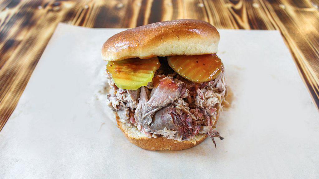 Pulled Pork Sandwich · Slow smoked pork shoulder, dressed in a tangy sop sauce, served on a toasted bun, our house-made sweet and tangy BBQ sauce, and pickles.