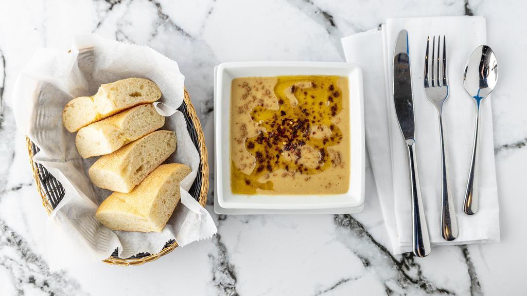 Bysar · Traditional split pea soup garnished with olive oil, cumin, and pepper, served with spicy olives and homemade bread.