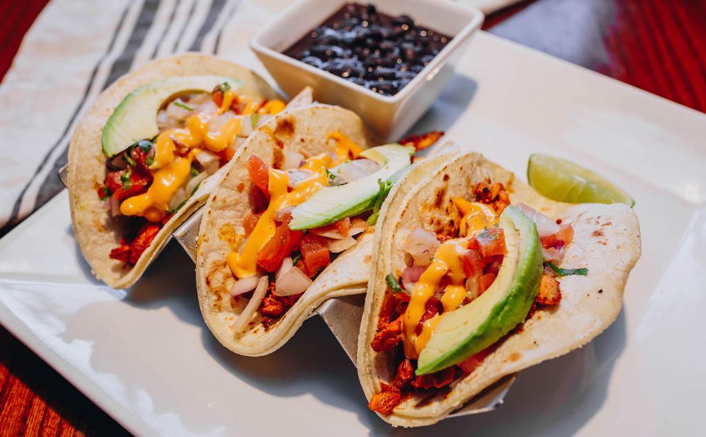 Marinated Grilled Chicken Tacos · Three corn or flour tortillas filled with grilled chicken, fresh pico de gallo, avocado, and creamy chipotle sauce. Served with black beans and limes.