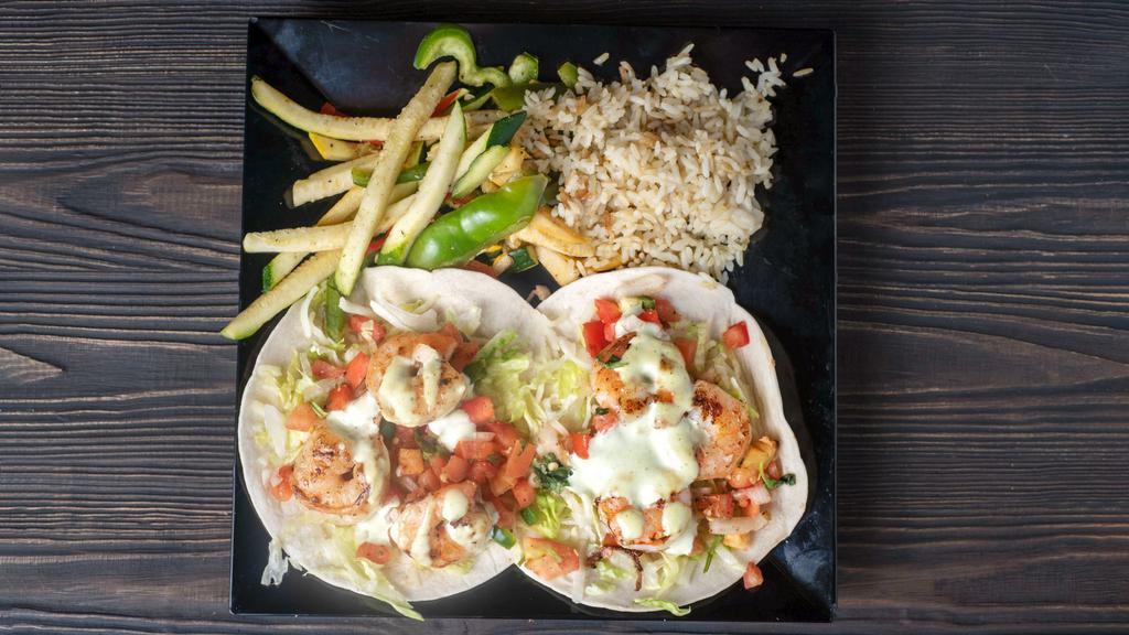Shrimp Tacos · Flour tortilla tacos dressed with roasted garlic sauce, lettuce, cheese and pico de gallo served with vegetables and rice.