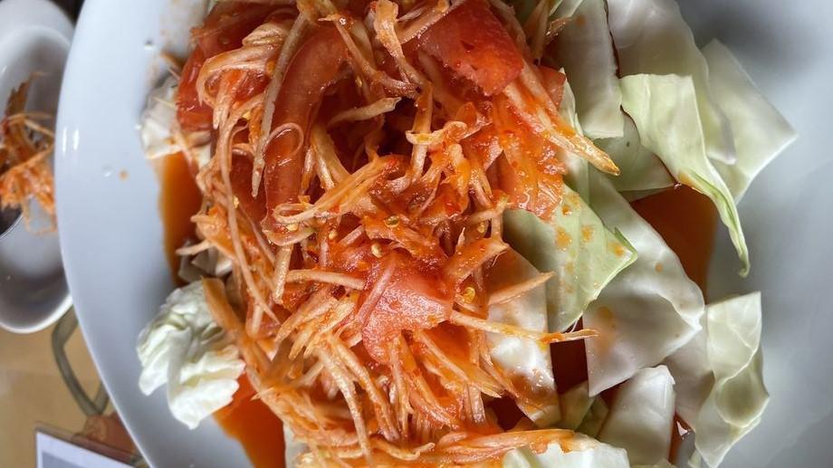 Som Tum (Papaya Salad) · Papaya salad. A popular sliced green papaya and carrots tossed with tomatoes, grounded garlic, thai chili peppers, lime juice, and fish sauce. Served on top of the cabbage.