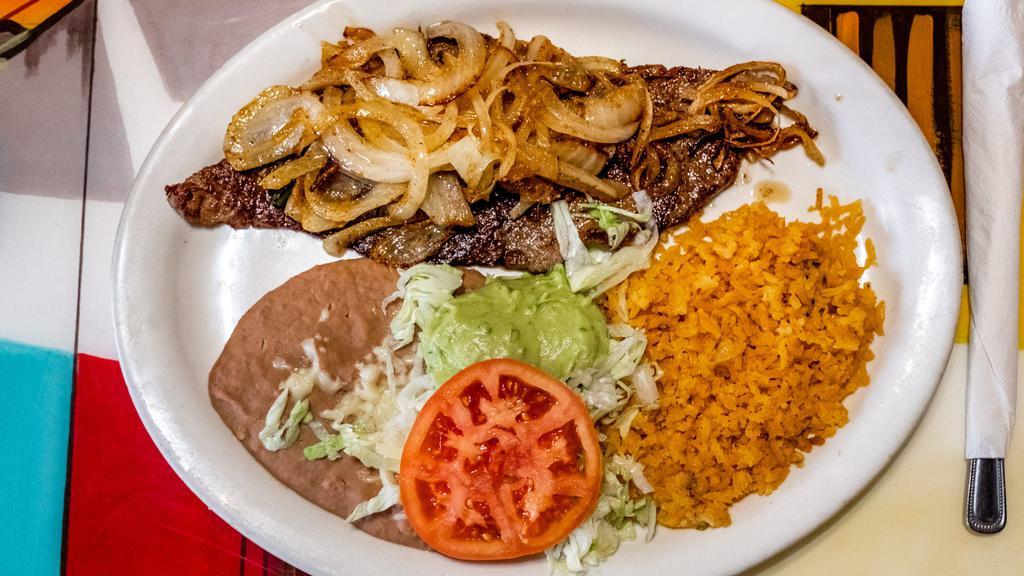 Carne Asada · Traditional thinly sliced steak. Served with rice, beans, sautéed onions, guacamole, lettuce, and tortilla.