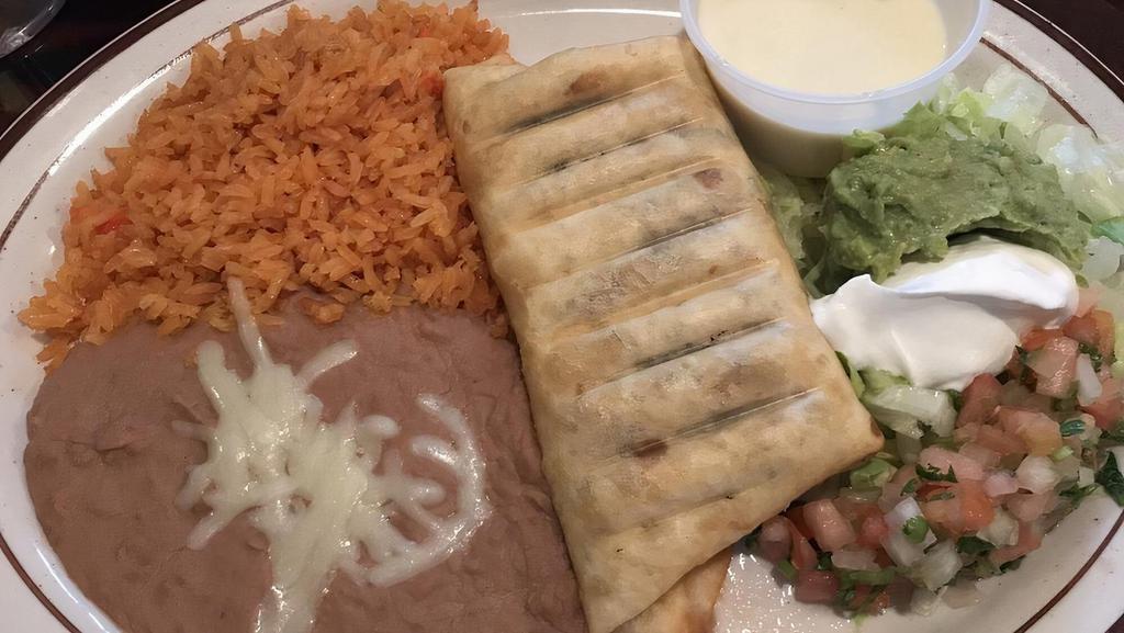Chimichanga Lunch · We stuff a flour tortilla with your choice of shredded beef or chicken, then deep-fried to a golden brown. Topped with cheese sauce, lettuce, sour cream, pico de gallo, and guacamole. Served with rice and beans.