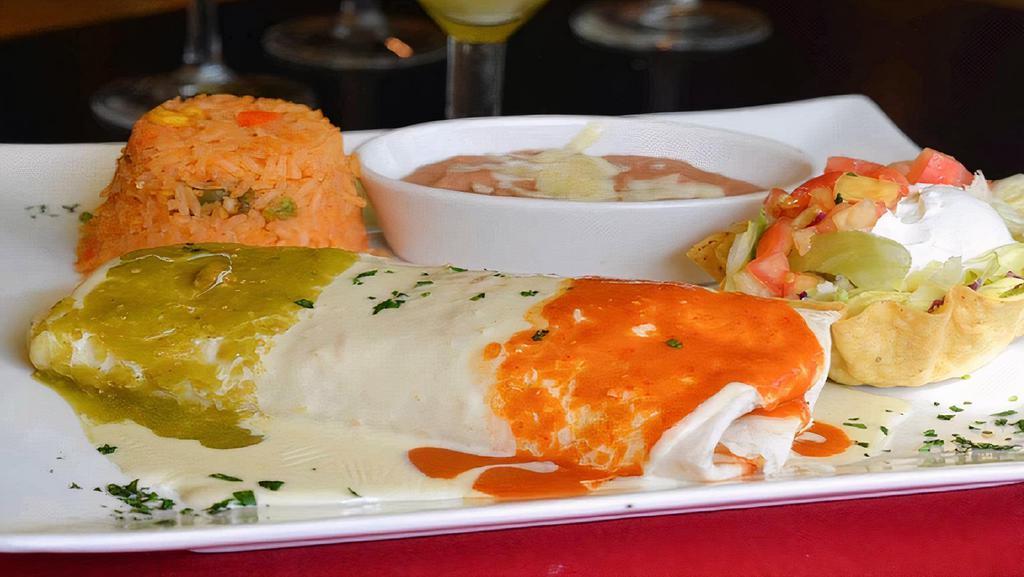 Burrito Al Carbón · A flour tortilla filled with marinated skirt steak, topped with nacho cheese and green and red tomatillo sauce. Served with rice, beans, lettuce, tomatoes, and sour cream.