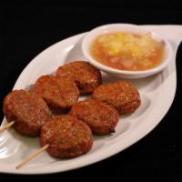 Tod Mun Moo · Skewered Thai meatballs with coconut flakes, kaffir lime leaves, lemongrass and spices. Serv...