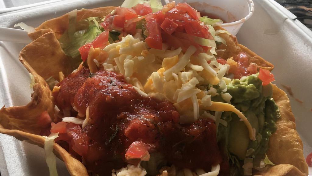 Taco Salad · Flour tortilla bowl filled with ground beef, shredded chicken, rice, refried beans, cheese, tomatoes, jalapeños, lettuce, sour cream, and guacamole.