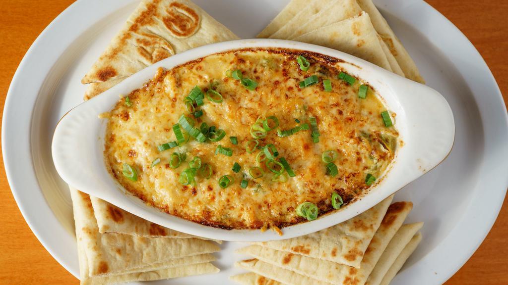 Crab Dip · Fresh crab meat seasoned and baked in a cheesy cream sauce with green peppers and white onion, topped with chives, and served with warm pita triangles