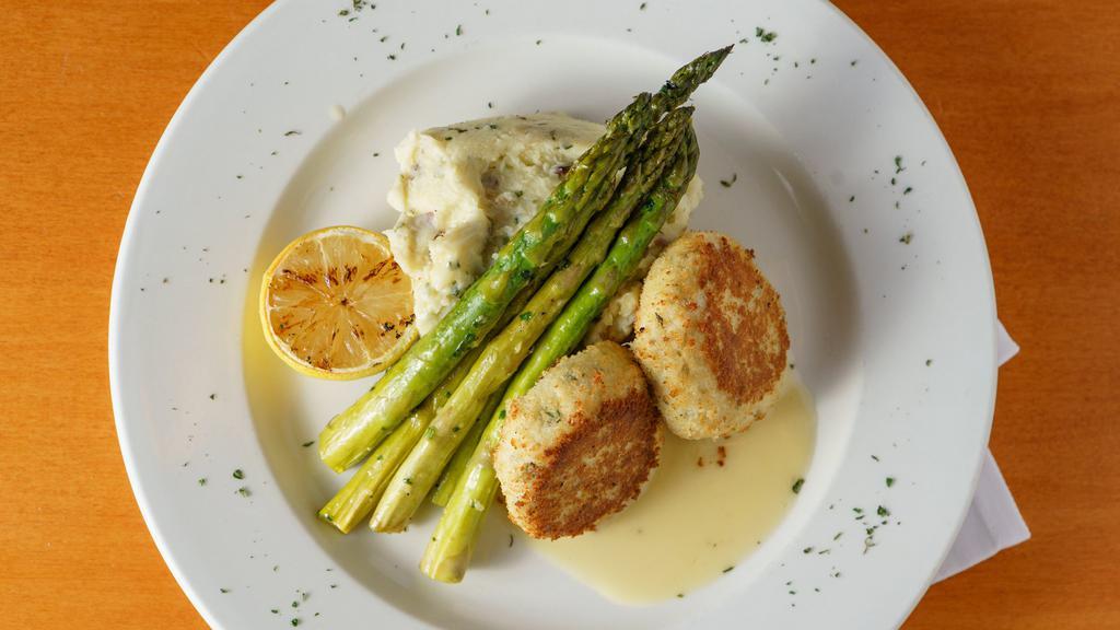 Crab Cakes · Two New England-style crab cakes, pan-seared and served with mashed potatoes and asparagus, dressed with lemon butter sauce.