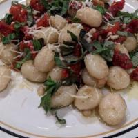 Pesto Gnocchi Appetizer · potato dumplings sautéed with pesto, pine nuts and sun dried tomatoes, topped with fresh bas...