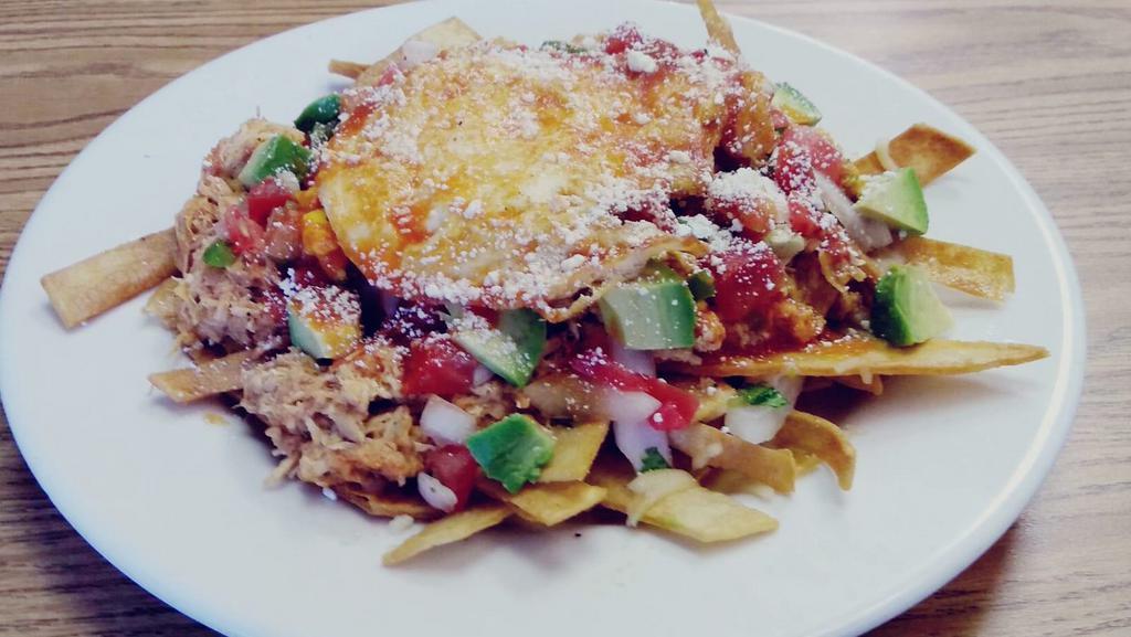 Chilaquiles · Tortilla strips simmered in red sauce, served with melted cheese, shredded chicken and a fried egg.
