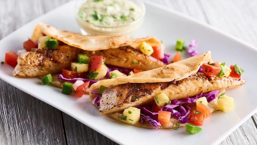 Fish Tacos · Grilled, blackened, or fried tilapia, roasted chile mayo, red cabbage, pineapple pico de gallo, white rice & black beans. Grilled and blackened fish taco can be prepared gluten free.