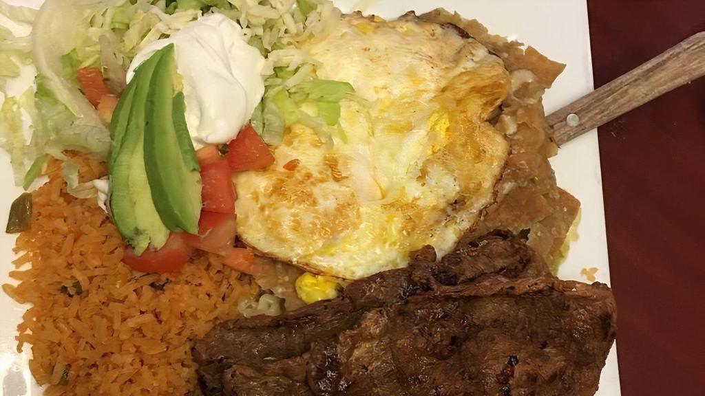 Chilaquiles  · 2 Fried Eggs & Carne Asada on a bed of tortilla Chips with green sauce on top. Comes with rice and Cream Salad