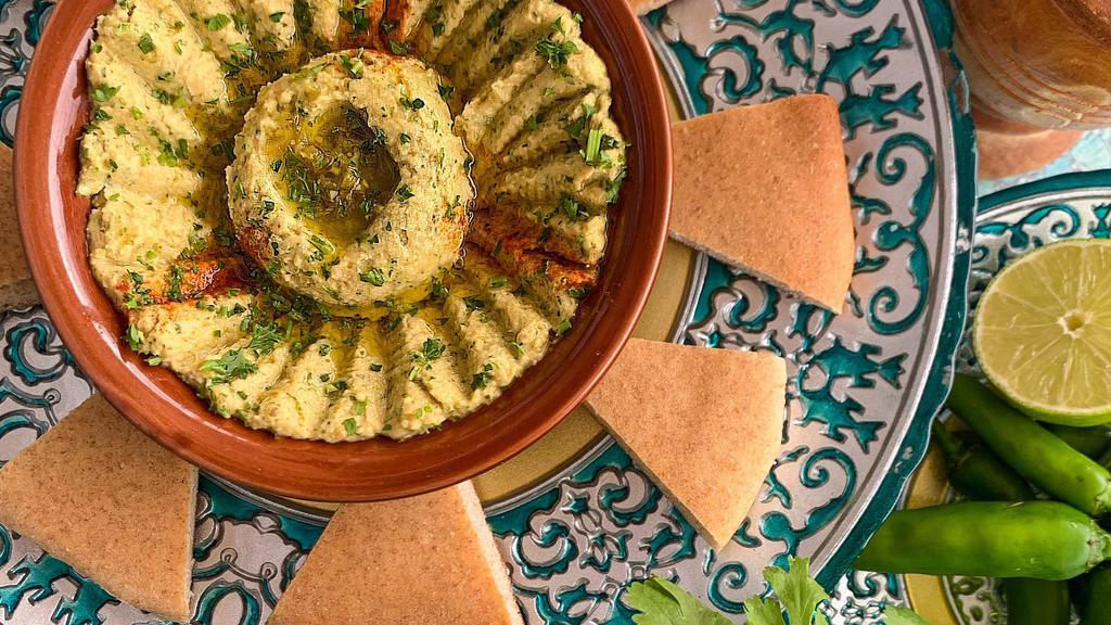 Spicy Jalapeño Cilantro Hummus · Spicy. A delicious spread of chickpeas, olive oil, lemon juice, fresh cumin, a hint of garlic, jalapeño, and tahini sauce. Served with our homemade pita bread.
