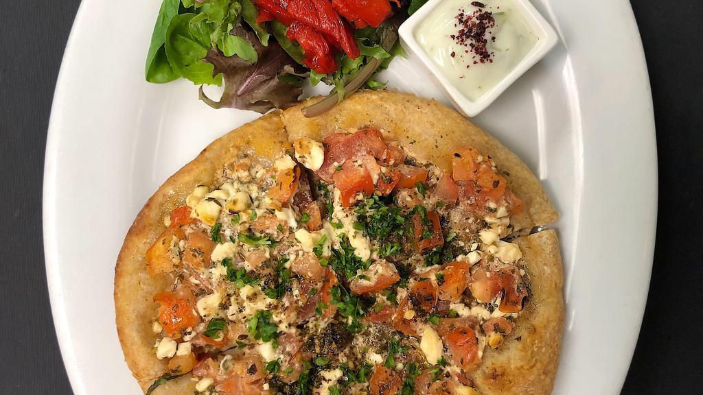 Jebneh · Mediterranean small pizza. Crumbled feta, diced tomatoes, fresh oregano with lemon olive oil dressing.