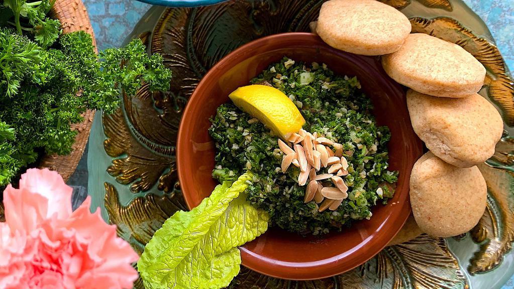Tabbouleh Salad · Finely organic chopped parsley mixed with organic cracked wheat, diced tomatoes, cucumbers, and fresh mint in a lemon-olive oil dressing topped with raw almond slivers and served with pita pieces.