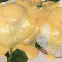 Kostas Eggs Benedict · Split English muffin topped with tomato, spinach, black forest ham, 2 easy eggs and hollanda...