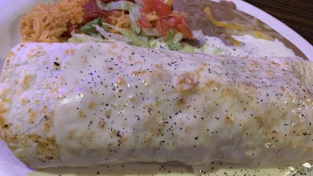 Burrito Del Mar · Big flour tortilla filled with grilled shrimp, steak, chicken, onions, bell peppers, and tomatoes. Topped with our house cheese dip. Served with rice and refried beans.