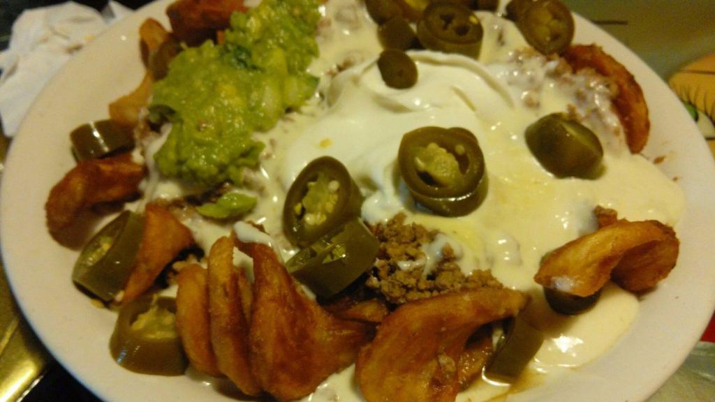 Papa Nachos · Fried sidewinder potato your choice ground beef or shredded chicken topped with white queso, guacamole, sour cream and jalapeños.