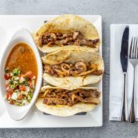 Tacos Al Carbon · Three flour tortillas stuffed with slices of steak or chicken, grilled onions, nacho cheese,...
