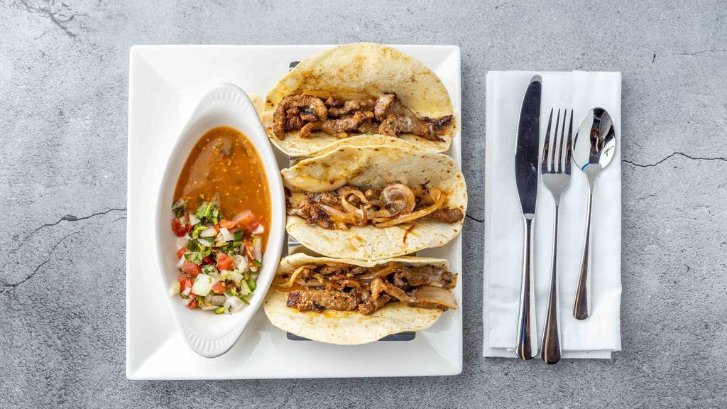 Tacos Al Carbon · Three flour tortillas stuffed with slices of steak or chicken, grilled onions, nacho cheese, pico de gallo, and tomato sauce.