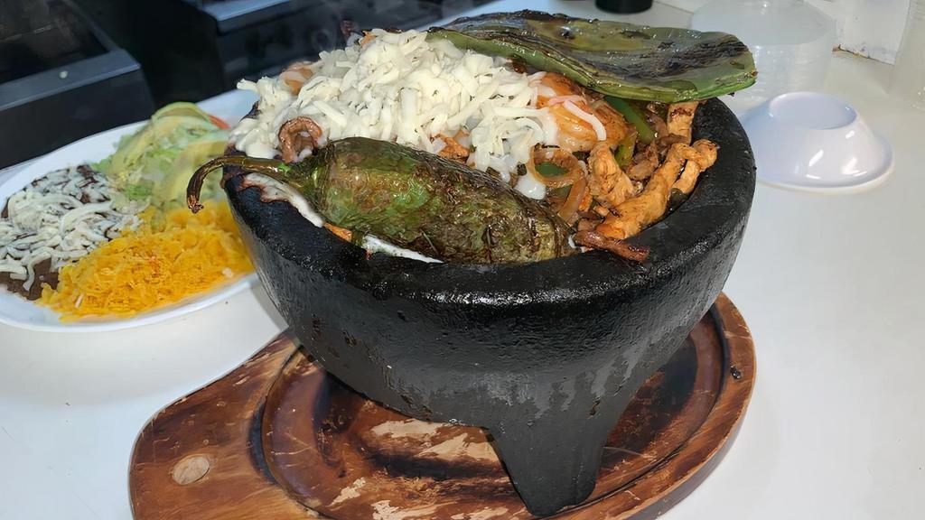 Molcajete Mix · Sizzling fajitas with chicken, steak, shrimp
and Mexican sausage cooked with cactus,
bell peppers & onions garnished with cilantro, with black refried beans, rice, lettuce, tomatoes, avocado, sour cream and limes on the side. Served with your choice of flour or corn tortillas.