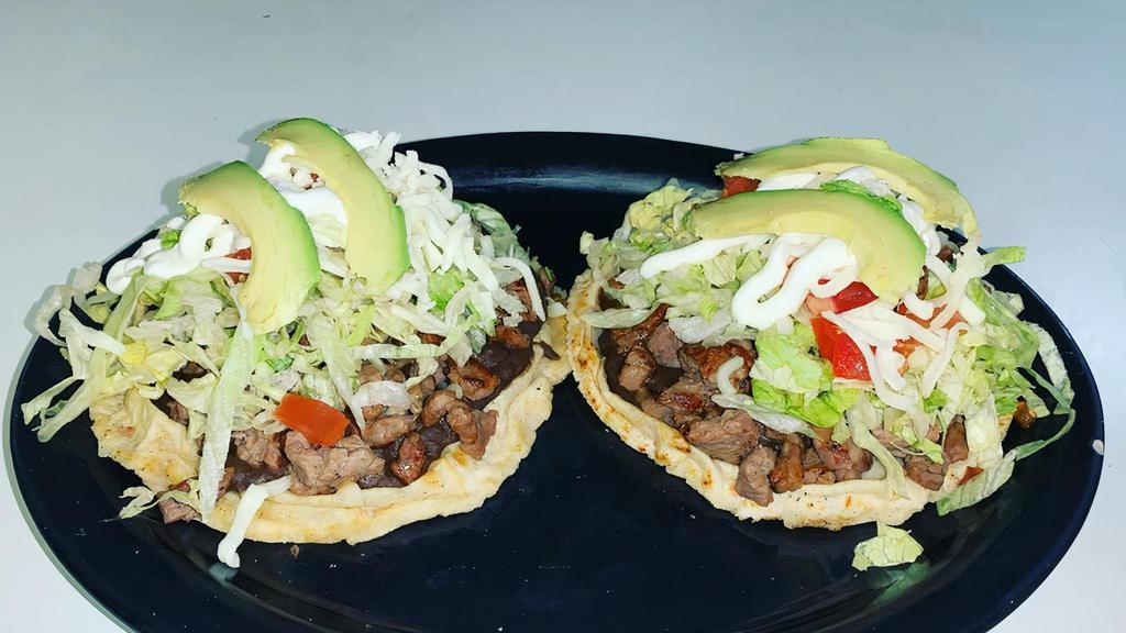 Sopes · Two round thick flattened pieces of grilled corn dough topped with your choice of meat, black refried beans, lettuce, tomatoes, Mexican cheese, sour cream, cilantro and avocado.