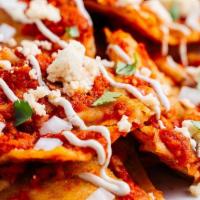 Chilaquiles · Tortilla chips marinated in homemade salsa roja topped with queso fresco, onions, and cream ...
