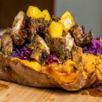 Carribean Queen · Spicy. Soft sweet potato stuffed with jerk chicken, on a sheet of purple grilled cabbage, dr...
