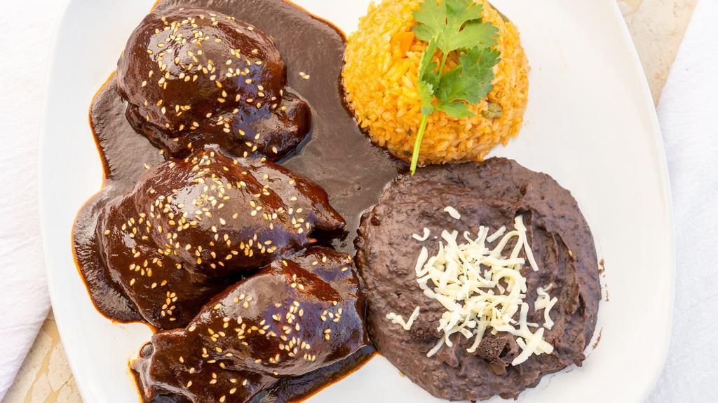 Mole Poblano · Boneless chicken thighs with our homemade mole sauce. This traditional dish from Puebla, Mexico, is made with different Mexican chiles, chocolate and spices (not spicy). Served with rice and refried black beans.