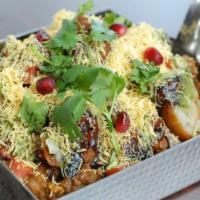 Aloo Tikki Chaat · Crushed potato cutlets covered in spiced chickpea masala, tomatoes, onions, and chutneys. (v...