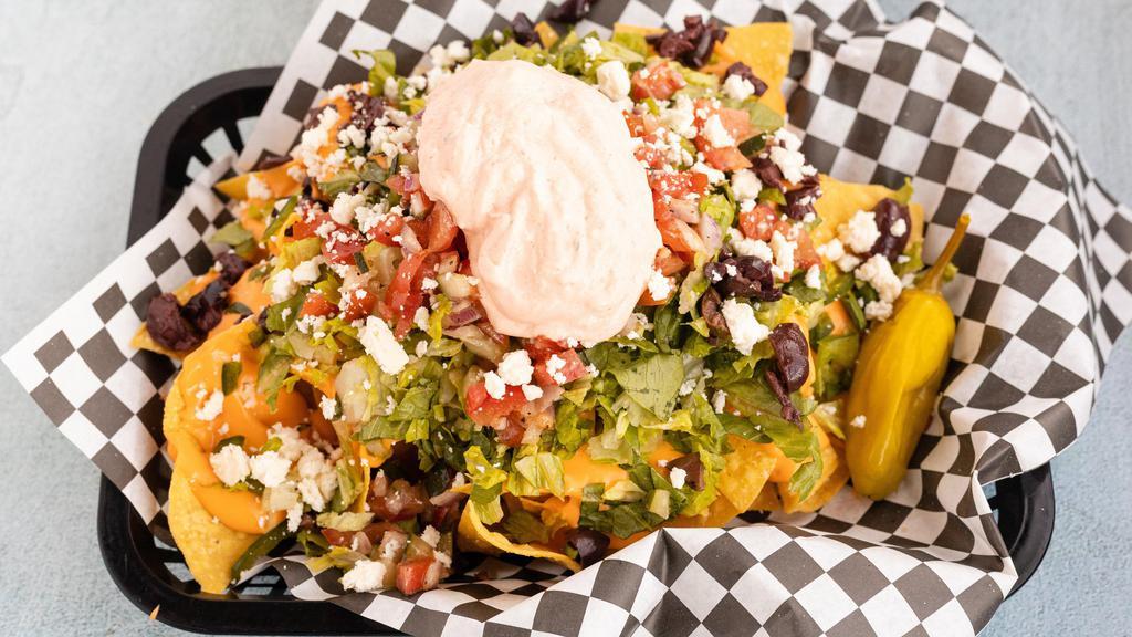 Greek Nachos · Lettuce, Greek salsa, banana peppers, bell peppers, cheese sauce, topped with feta and drizzled with our spicy tzatziki. Add chicken for an additional charge.