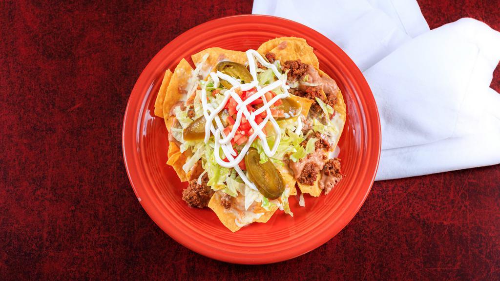 Nachos Supreme · A bed of crispy tortilla chips topped with beans, shredded lettuce, diced tomatoes, cheese dip, sour cream, jalapeños and your choice of ground beef or chicken.