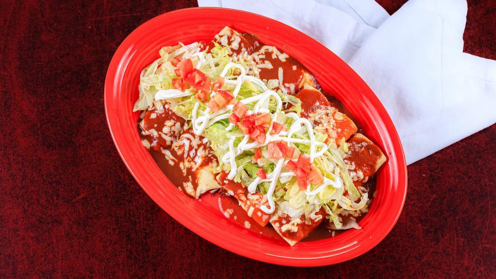 Enchiladas Supremas · Five enchiladas (one chicken, one shredded brisket, one ground beef, one bean, and one cheese enchilada) with lettuce and sour cream on top.