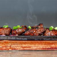 Korean Short Ribs · Traditional Korean short ribs served on a cast iron sizzle plate with red onions, garlic and...