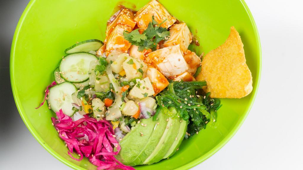 Veggi Poké · Vegan. Tofu, sweet heat sauce, avocado, cucumber, red cabbage, cilantro, seaweed salad, topped with pineapple salsa and fried wonton chips.