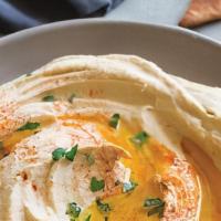 Hummus · Traditional Lebanese Hummus drizzled with olive oil and served with warm pita bread.