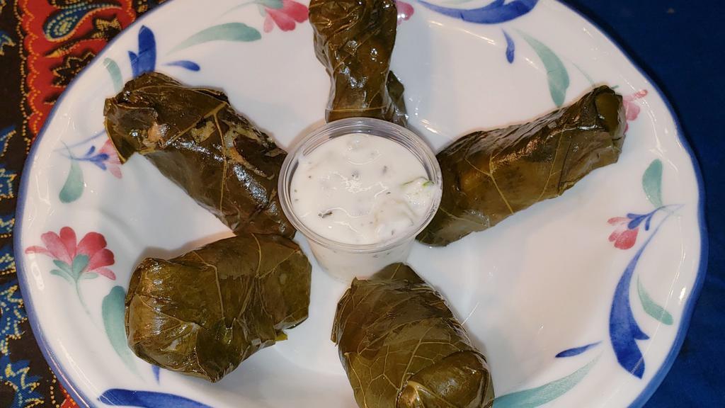 Stuffed Grape Leaves · Cooked grapevine leaves stuffed with rice and spices, served with a side of cucumber sauce, or garlic sauce.