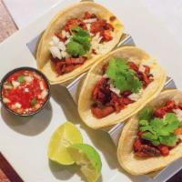 Tacos Al Pastor · Corn tortillas with grilled pork marinated in a pineapple adobo, topped with cilantro and on...