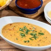 Smoky Queso · Our signature queso kicked-up with roasted red chile tomatillo salsa and cilantro.
